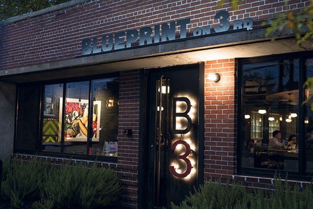Brick storefront and illuminated B3 sign at Blueprint on 3rd in Birmingham at dusk