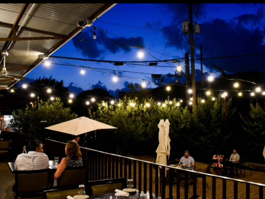 Outdoor patio dining area at Blueprint on 3rd in Birmingham, Alabama, featuring string lights and upscale casual ambiance