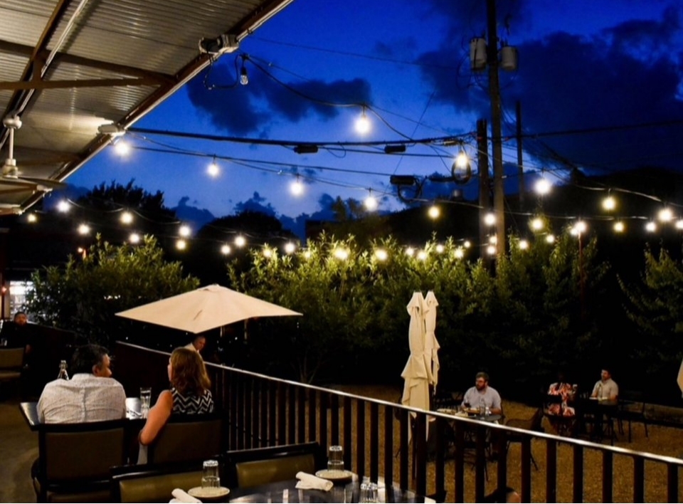 Guests seated on Blueprint on 3rd's outdoor patio beneath string lights at dusk in Birmingham