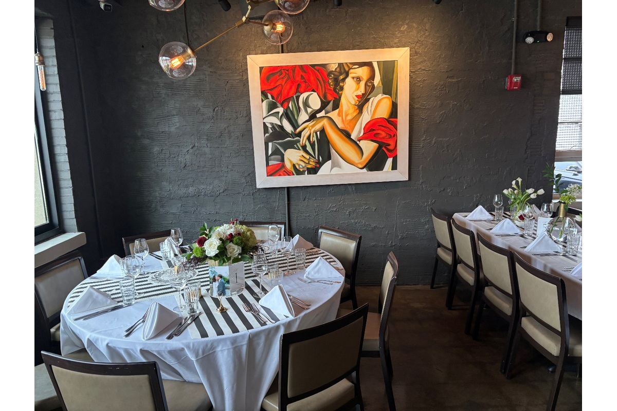 Private dining room at Blueprint on 3rd in Birmingham with white table settings, floral centerpieces, contemporary artwork, and warm industrial details