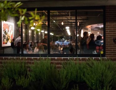 Guests dining inside Blueprint on 3rd, seen through the restaurant's large windows in Birmingham