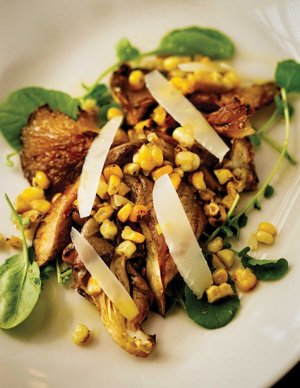 Grilled chicken with sweet corn, fresh greens, and shaved cheese on a plate, representing special occasion dining in Birmingham, Alabama