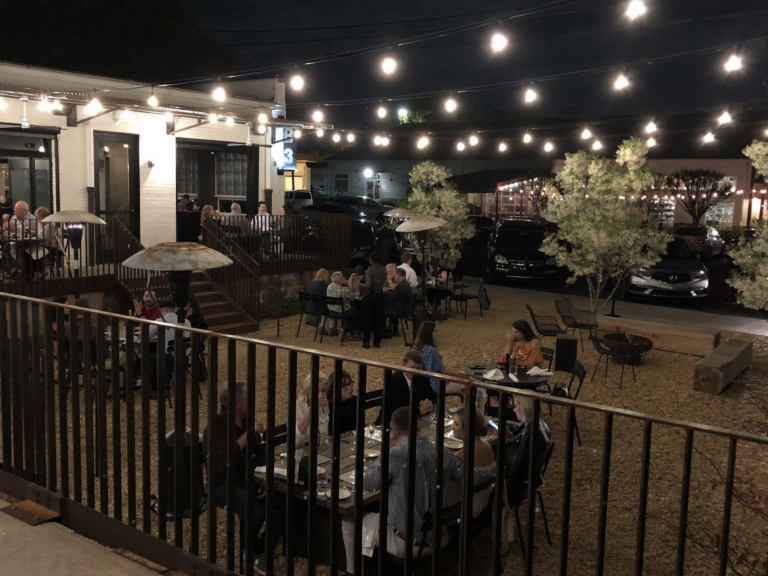 Guests dining on the patio at Blueprint on 3rd in Birmingham at night under string lights